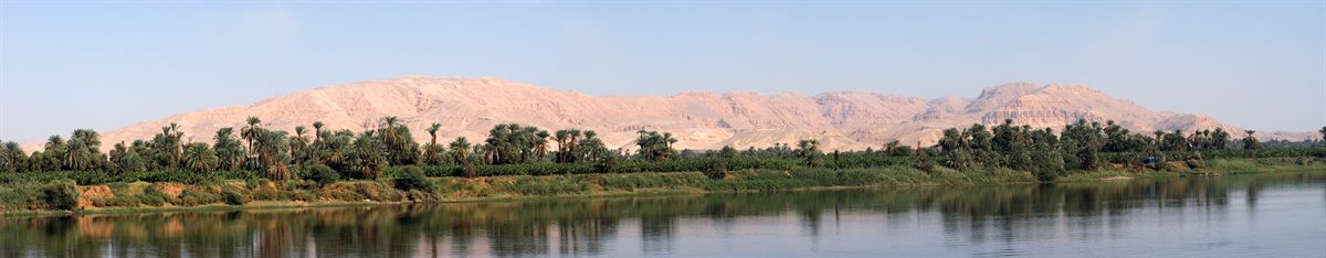 Palm-lined bank of the Nile with desert hills beyond